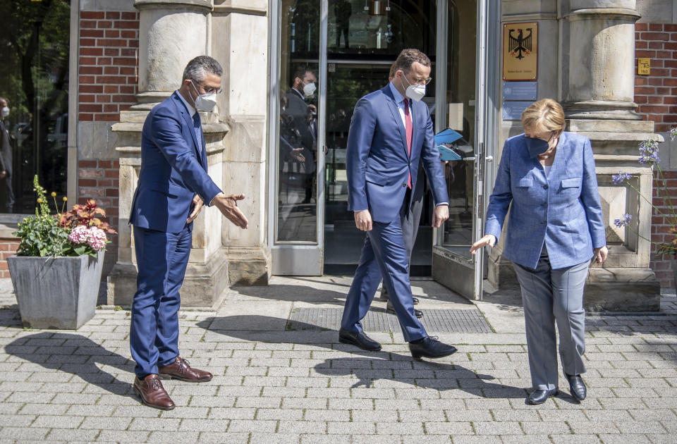 German Chancellor Angela Merkel, Jens Spahn, Federal Minister of Health, and Lothar Wieler, President of the Robert Koch Institute (RKI), from right, prepare for a picture in front of the entrance to the RKI in Berlin, Germany, Tuesday, July 13, 2021. Merkel visited the health ministry's leading institute in the Corona pandemic at the invitation of Health Minister Spahn. (Michael Kappeler/Pool via AP)