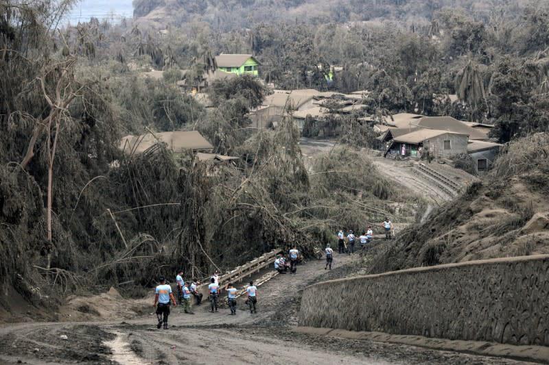 Police officers guard a road nearby the errupting Taal Volcano in Talisay