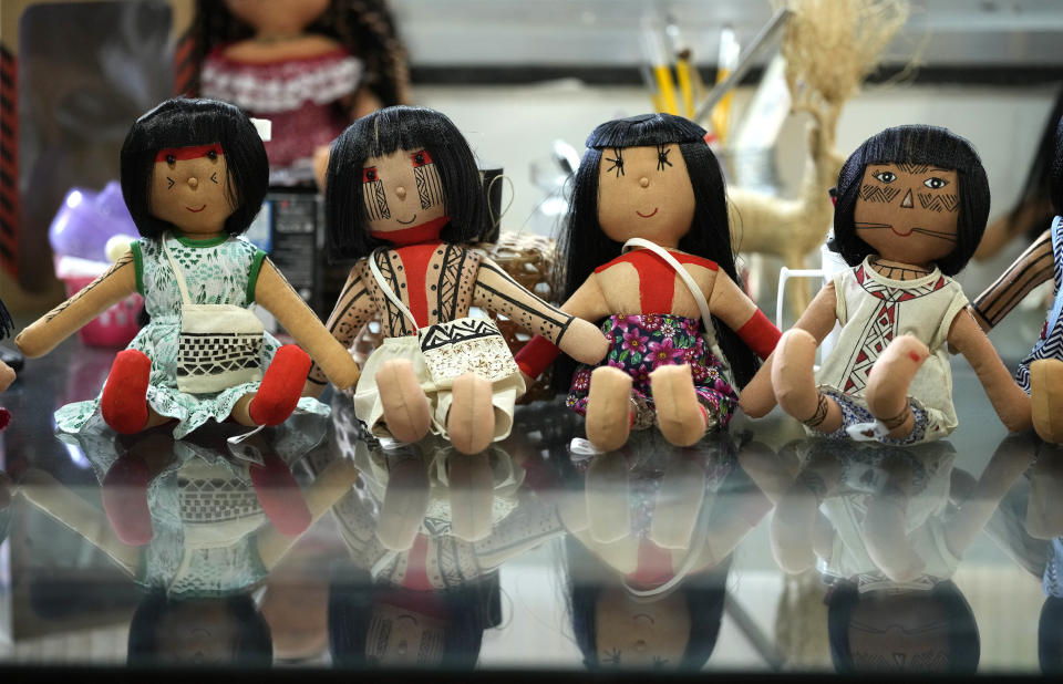 Dolls bearing faces and body paints of different Indigenous groups are displayed on a table at a sewing workshop in Rio de Janeiro, Brazil, Tuesday, May 24, 2022. Each one of them is hand sown, dressed in clothes created by Luakam Anambe, of Brazil’s Anambe Indigenous group, and carefully painted by her daughter Atyna Pora. (AP Photo/Silvia Izquierdo)