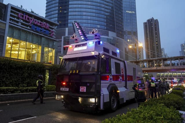 Riot police gather near a water cannon truck as they face off with demonstrators 