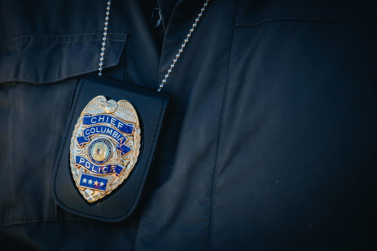 Columbia Police Chief Geoff Jones’ police badge sits against his coat as he speaks during a press conference.