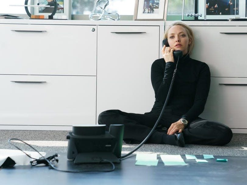 Amanda Seyfried dressed in black on the phone sitting on the floor