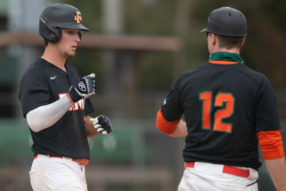 Florida A&M University outfielder Grant Rowell (7) fist bumps with a coach at first base during a game between FAMU and Mercer University Tuesday, March 16, 2021. 