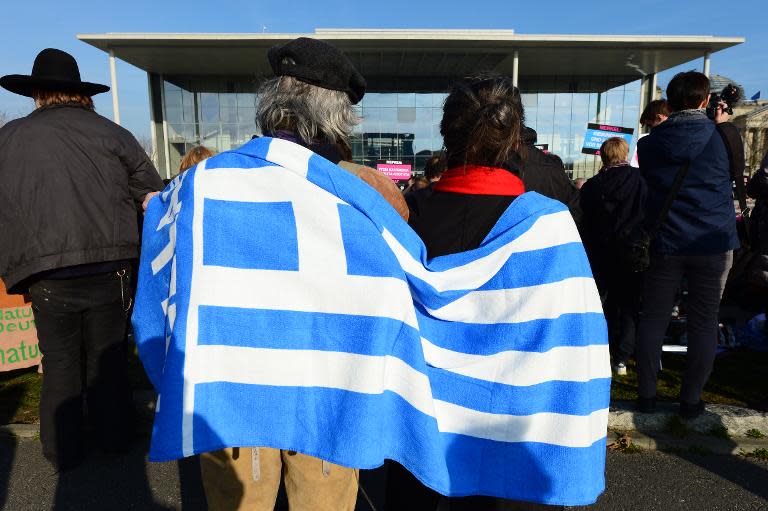 Two people draped in a Greek flag stage a protest in front of the chancellery in Berlin prior to a meeting of the leaders of Greece and Germany on March 23, 2015