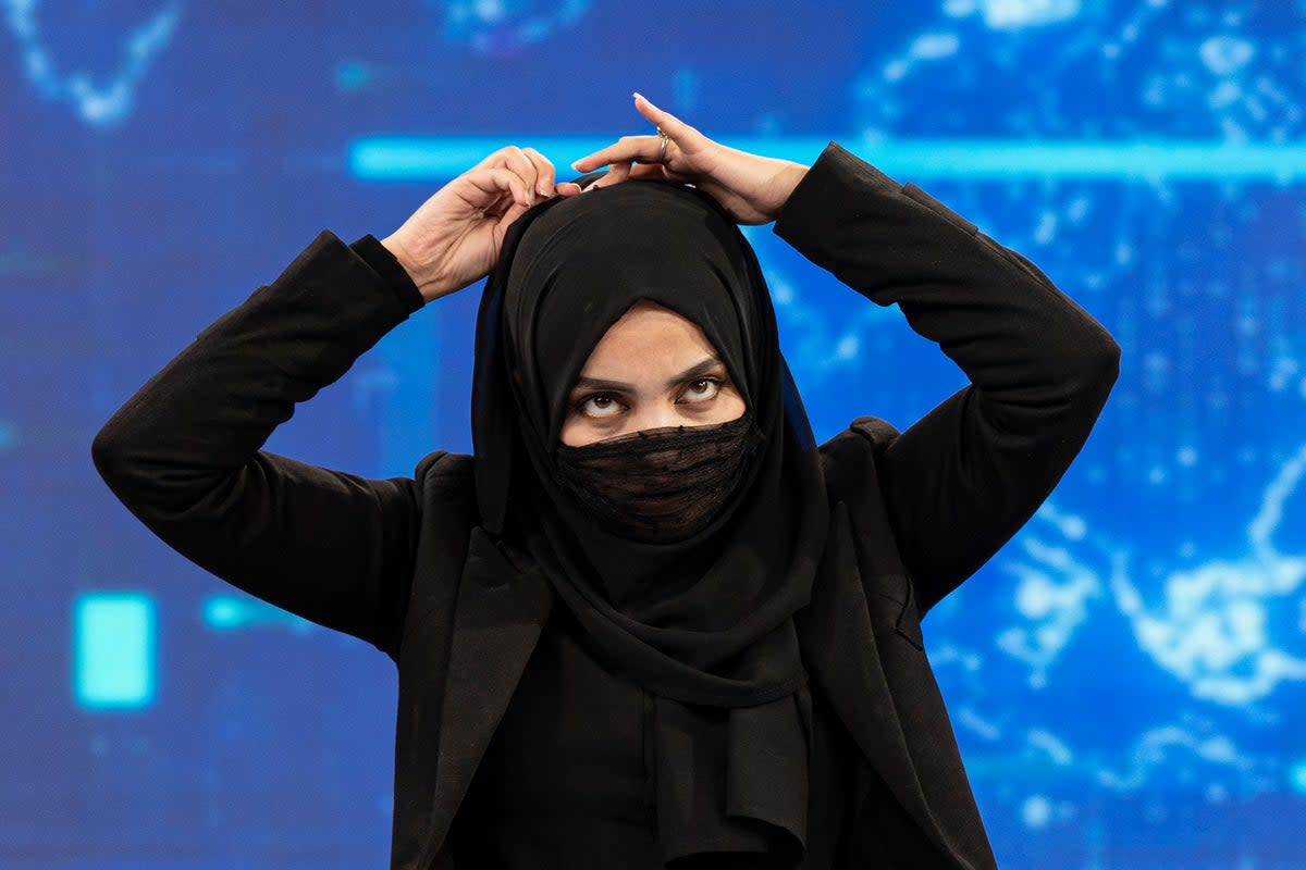 A female presenter for TOLOnews covers her face during a live broadcast at Tolo TV station in Kabul (AFP via Getty Images)