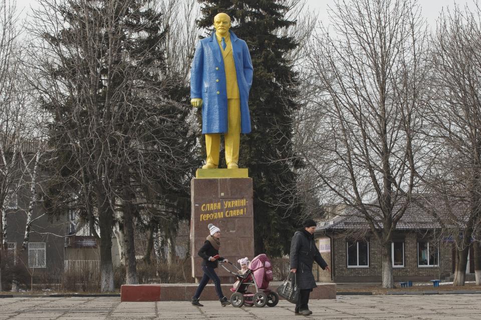 FILE - People walk by a statue of Vladimir Lenin, painted in the colors of Ukraine's national flag, in Velyka Novosilka, Ukraine, on Thursday, Feb. 19, 2015. In a speech three days before invading Ukraine in 2022, Russian President Vladimir Putin appeared to keep Lenin at arm's length, dismissing Ukraine’s sovereign status as an illegitimate holdover from Lenin's era, when it was a separate republic within the Soviet Union. (AP Photo/Vadim Ghirda, File)