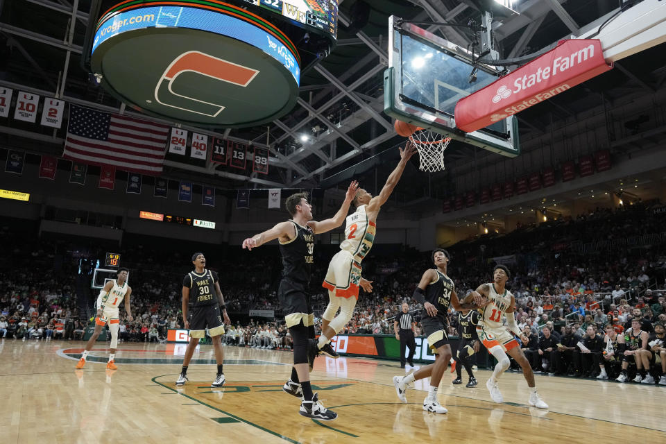 Miami guard Isaiah Wong (2) jumps to score past Wake Forest forward Matthew Marsh (33) and Wake Forest forward Bobi Klintman (34) during the first half of an NCAA college basketball game, Saturday, Feb. 18, 2023, Coral Gables, Fla. (AP Photo/Rebecca Blackwell)