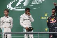 Formula One F1 - U.S. Grand Prix - Circuit of the Americas, Austin, Texas, U.S., 23/10/16. Mercedes' Lewis Hamilton of Britain rubs his eyes following his victory as second placed finisher and teammate Nico Rosberg of Germany (L) and third placed Red Bull's Daniel Ricciardo of Australia (R) look on during the victory ceremony. REUTERS/Adrees Latif