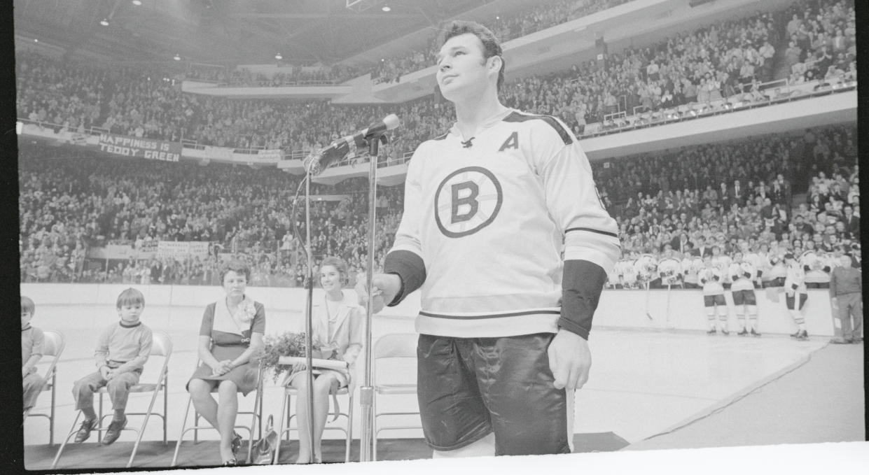 Ted Green, Boston Bruins' defenseman (right) looks up at Boston Garden 14,000 fans who applaude him during ceremonies honoring him. Looking on are Ted's wife Pat (2nd right), his mother Mrs. John Green, and one of Ted's children, Chris. The Bruins defenseman was honored for his amazing comeback from a head injury which kept him from playing a year. (Getty Images)