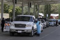 FILE - In this July 21, 2020, file photo, health care workers take information and samples from people waiting to be tested for the coronavirus in Pleasanton, Calif. Gov. Gavin Newsom said Wednesday, Aug. 12, 2020, that California was turning the corner in its fight against the coronavirus pandemic, citing a significantly lower number of confirmed new cases as the state begins to clear backlogged cases from a data failure. (AP Photo/Ben Margot, File)