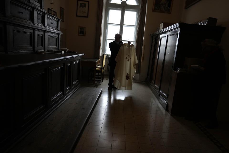 Father Tadeusz Rozmus shows a cassock belonging to the late Pope Emeritus Benedict XVI during an interview with the Associated Press in the San Tommaso Da Villanova Parrish church in Castel Gandolfo, in the hills south of Rome, Tuesday Jan. 3, 2023. Benedict's death has hit Castel Gandolfo's "castellani" particularly hard, since many knew him personally, and in some ways had already bid him an emotional farewell on Feb. 28, 2013, when he uttered his final words as pope from the palace balcony overlooking the town square. (AP Photo/Alessandra Tarantino)