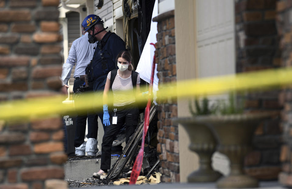 Investigators examine a house where five people were found dead after a fire in suburban Denver on Wednesday, Aug. 5, 2020. Three people escaped the fire by jumping from the home's second floor. Investigators believe the victims were a toddler, an older child and three adults. Authorities suspect was intentionally set. Witnesses told firefighters that three people on the second floor of the burning home jumped to safety. A fire department spokesman said the fire's heat pushed back a police officer trying to rescue the people who were on the home's first floor. (AP Photo/Thomas Peipert)