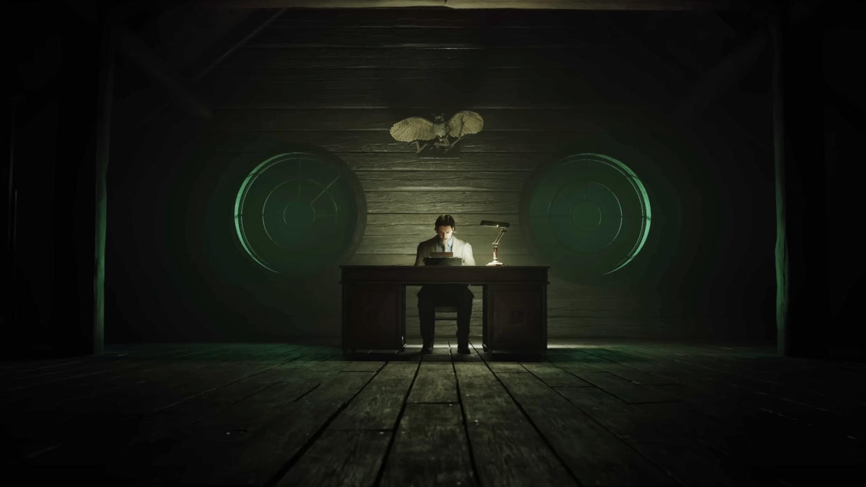  Alan Wake sitting at his desk in the Cauldron Lake cabin 