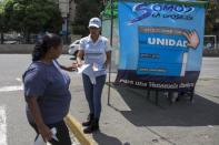 A supporter of MIN Unidad Party hands out a flyer with information on how to vote in Caracas, November 3, 2015. REUTERS/Marco Bello