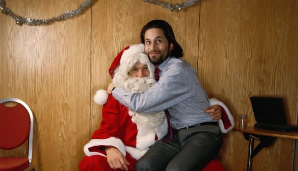 Man sitting on knee of man dressed as Santa