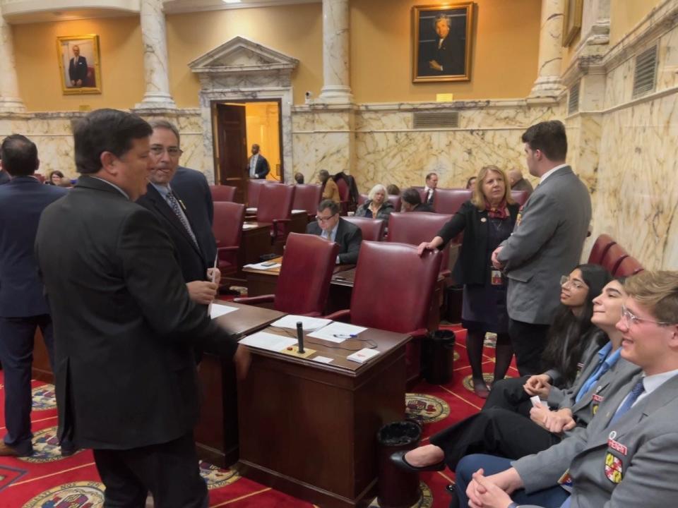 Sen. Mary Beth Carozza, R-Lower Shore, speaks to Stephen Decatur High School Senior William Kozma, a student page, on the Senate floor in Annapolis on Feb. 13, 2023. Sens. Johnny Mautz, R-Talbot, and Bryan Simonaire, R-Anne Arundel, chat with other student pages (in the foreground) before the evening session.