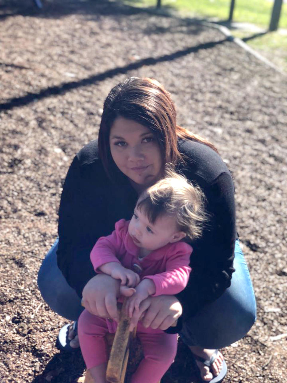 Pictured is Nikita Aldridge holding her young daughter in a park. 
