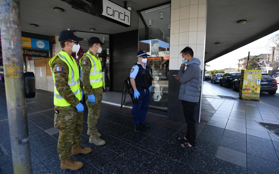 NSW Police and Defence Force members speak to a man about compliance at Campsie in Sydney - JOEL CARRETT/EPA-EFE/Shutterstock