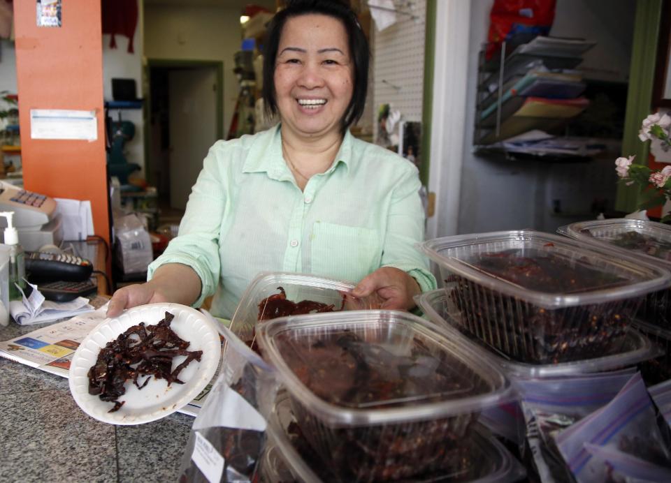 This March 13, 2014 photo shows Kimheng Chou showing off her homemade beef jerky at the Dessert Shop and Bakery in Lowell, Mass. Lowell now is home to one of the largest populations of Cambodians outside Cambodia. (AP Photo/Elise Amendola)