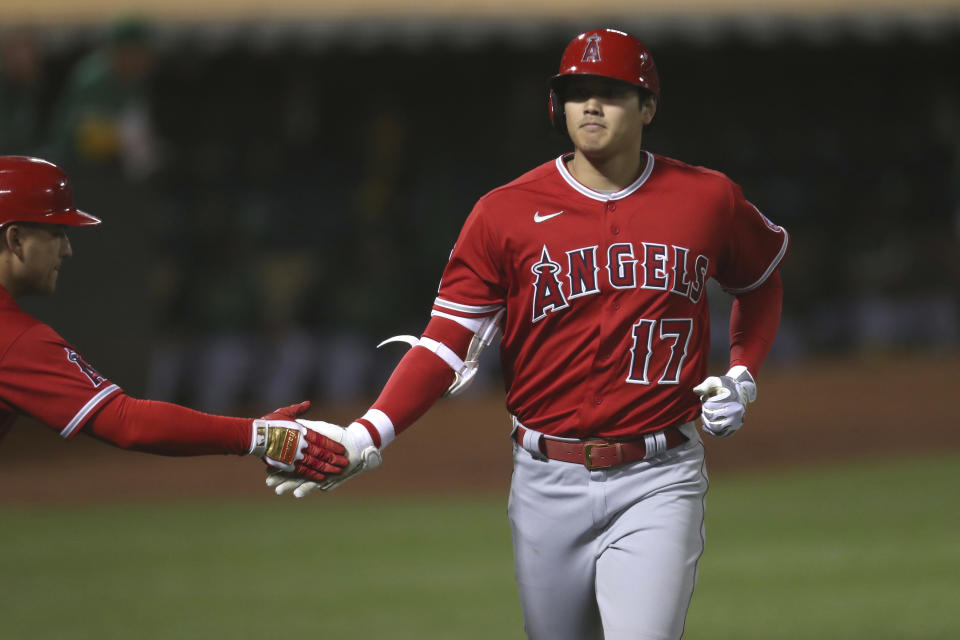 Los Angeles Angels' Shohei Ohtani, right, is congratulated by Jose Iglesias, left, after hitting a solo home run against the Oakland Athletics during the eighth inning of a baseball game in Oakland, Calif., Tuesday, June 15, 2021. (AP Photo/Jed Jacobsohn)