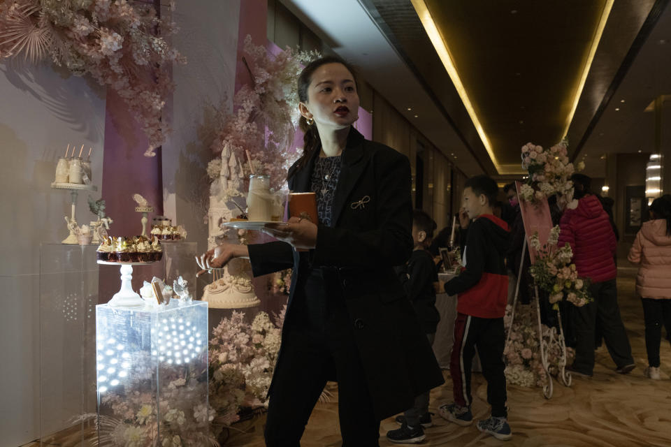 Ning Jingyuan, a wedding planner, supervises the setup for an unmasked wedding banquet in Beijing on Saturday, Dec. 12, 2020. The wedding planner reported 50% decrease in business over the previous year but is optimistic for the future as couples who pushed back their weddings are helping revitalize the industry as the pandemic fades and restrictions are lifted in China. (AP Photo/Ng Han Guan)