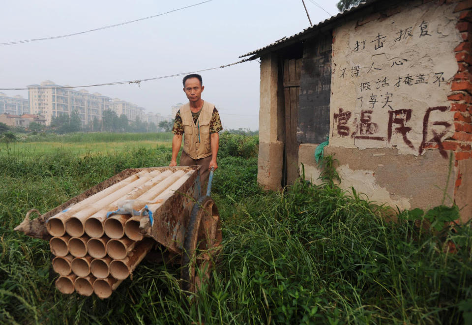 In a picture taken on June 6, 2010 Chinese farmer Yang Youde shows his homemade cannons on his farmland on the outskirts of Wuhan, in central China's Hubei province. Yang's improvised cannons, which are made out of a wheelbarrow, pipes and fire rockets, are used to defend his fields against property developers who want his land. Land seizures have been a problem for years in China, and have given rise to the term "nail house" to describe a holdout tenant or occupant, likening them to a nail refusing to be hammered down. CHINA OUT AFP PHOTO (Photo credit should read STR/AFP via Getty Images)