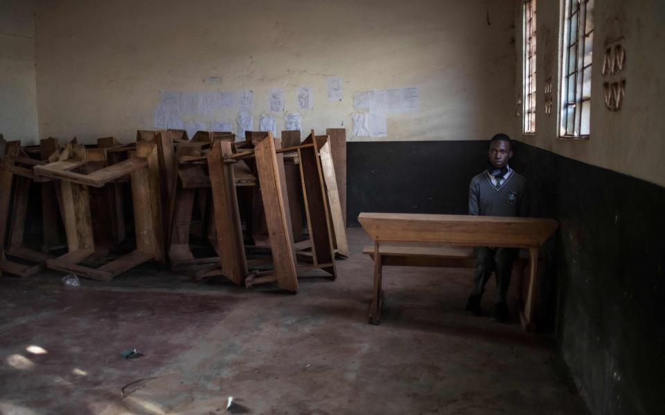 A student sits alone in a classroom after reporting back to school on day one of re-opening following an almost two-year closure of learning institutions as part of government measures to curb the spread of Covid-19 in Kampala, Uganda - BADRU KATUMBA /AFP 