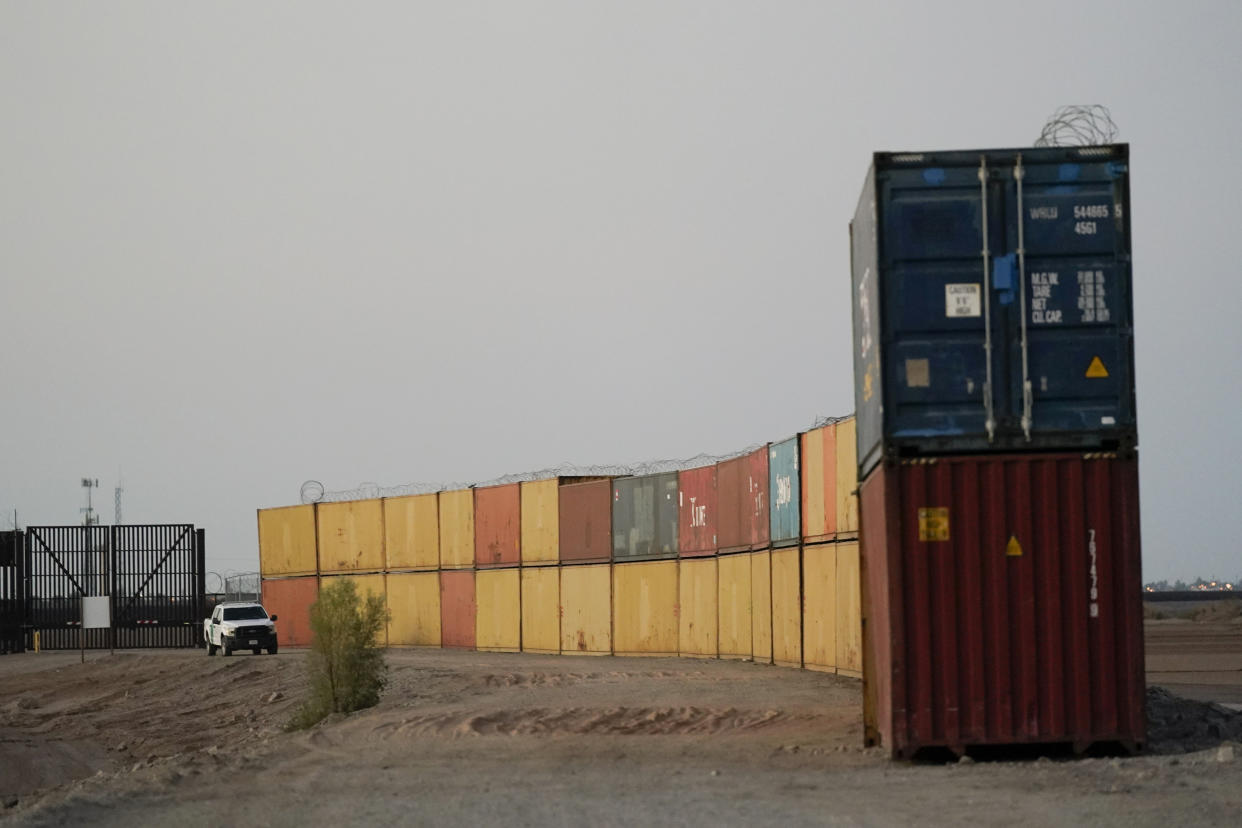 FILE - Border Patrol agents patrol along a line of shipping containers stacked near the border on Aug. 23, 2022, near Yuma, Ariz. The Cocopah Indian Tribe is welcoming the federal government's call for the state of Arizona to remove a series of double-stacked shipping containers placed along the U.S.-Mexico border near the desert city of Yuma, saying they are unauthorized and violate U.S. law. (AP Photo/Gregory Bull, File)