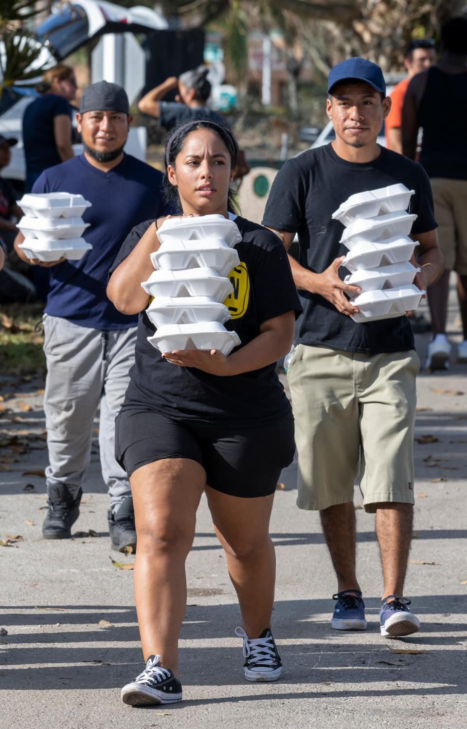 Residents of the flood-damaged Harmony Shores mobile home park in East Naples, Fla., and volunteers distribute meals to residents  on Wednesday, Oct. 5, 2022. Hurricane Ian's storm surge flooded the mobile homes.