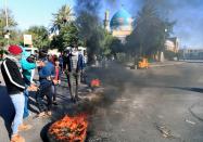 Iraqi demonstrators burn tires to block a street during ongoing anti-government protests in Baghdad