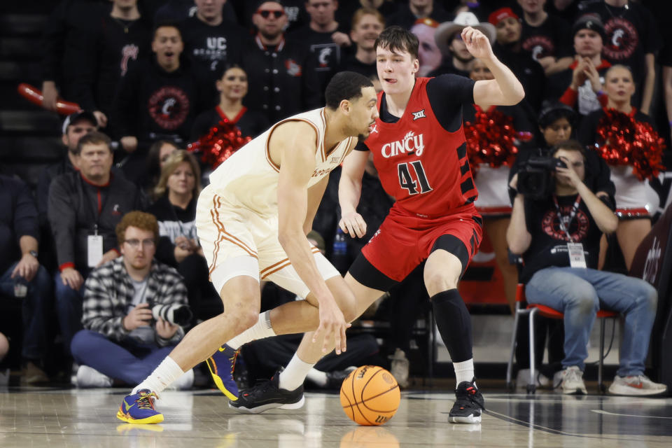 Texas' Dylan Disu, left, is defended by Cincinnati's Simas Lukosius during the first half of an NCAA college basketball game Tuesday, Jan. 9, 2024, in Cincinnati. (AP Photo/Jay LaPrete)