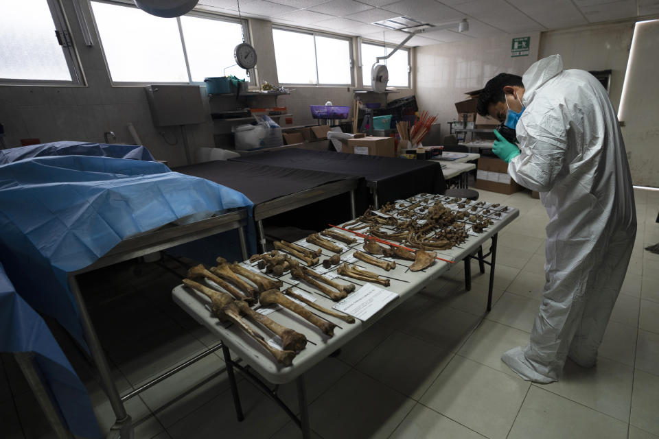 A technician photographs bone fragments at the forensic lab in Ciudad Victoria, Mexico, Friday, Feb. 4, 2022. President Andres Manuel Lopez Obrador promised in 2019 that investigators would have all the resources they needed. But the national commission, which was supposed to have 352 employees this year, still has just 89. (AP Photo/Marco Ugarte)
