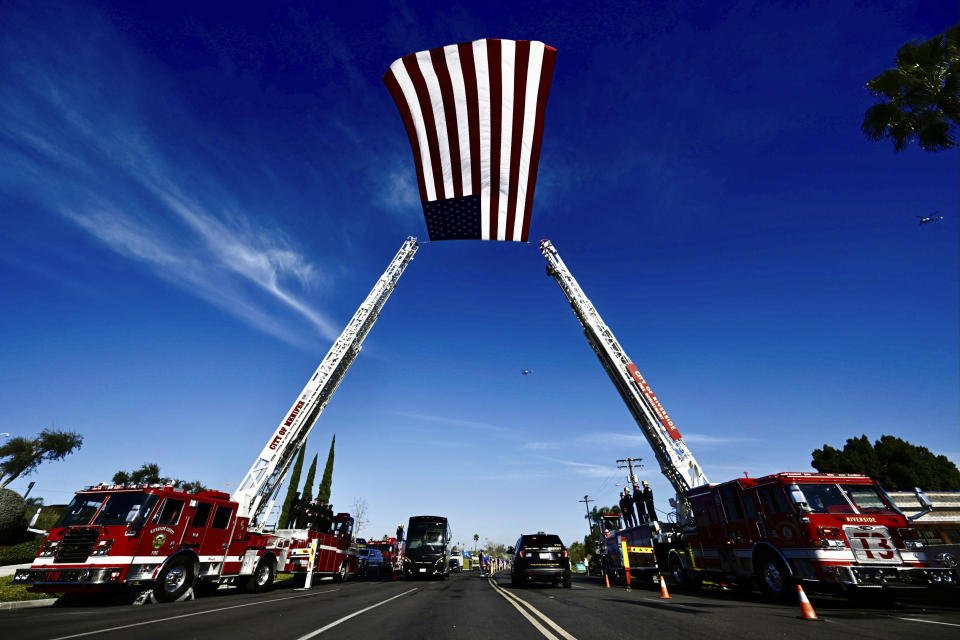 An American flag flies in the wind as Riverside County firefighters line up in Riverside, Calif., to honor the body of slain Riverside County Sheriff's deputy, Isaiah Cordero as the procession makes its way from the mortuary to the church for his funeral on Friday, Jan. 6, 2023. Cordero was shot and killed on Dec. 29, 2022, by a man with a violent criminal history during a traffic stop and the suspect later died in a shootout on a freeway, authorities said. (Watchara Phomicinda/The Orange County Register via AP)