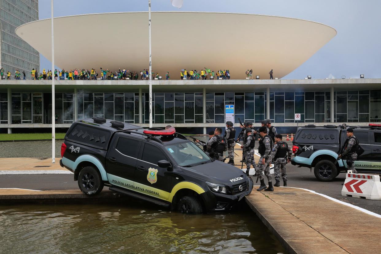 Members of the Federal Legislative Police stand next a vehicle that crashed into a fountain as supporters of Brazilian former President Jair Bolsonaro invade the National Congress in Brasilia on January 8, 2023. (Sergio Lima/AFP via Getty Images)