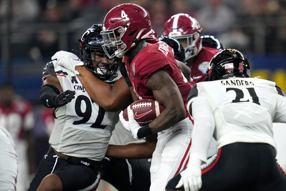 Alabama Crimson Tide running back Brian Robinson Jr. (4) finds running room as Cincinnati Bearcats defensive lineman Curtis Brooks (92) tries to make the tackle in the second quarter during the College Football Playoff semifinal game at the 86th Cotton Bowl Classic, Friday, Dec. 31, 2021, at AT&T Stadium in Arlington, Texas.