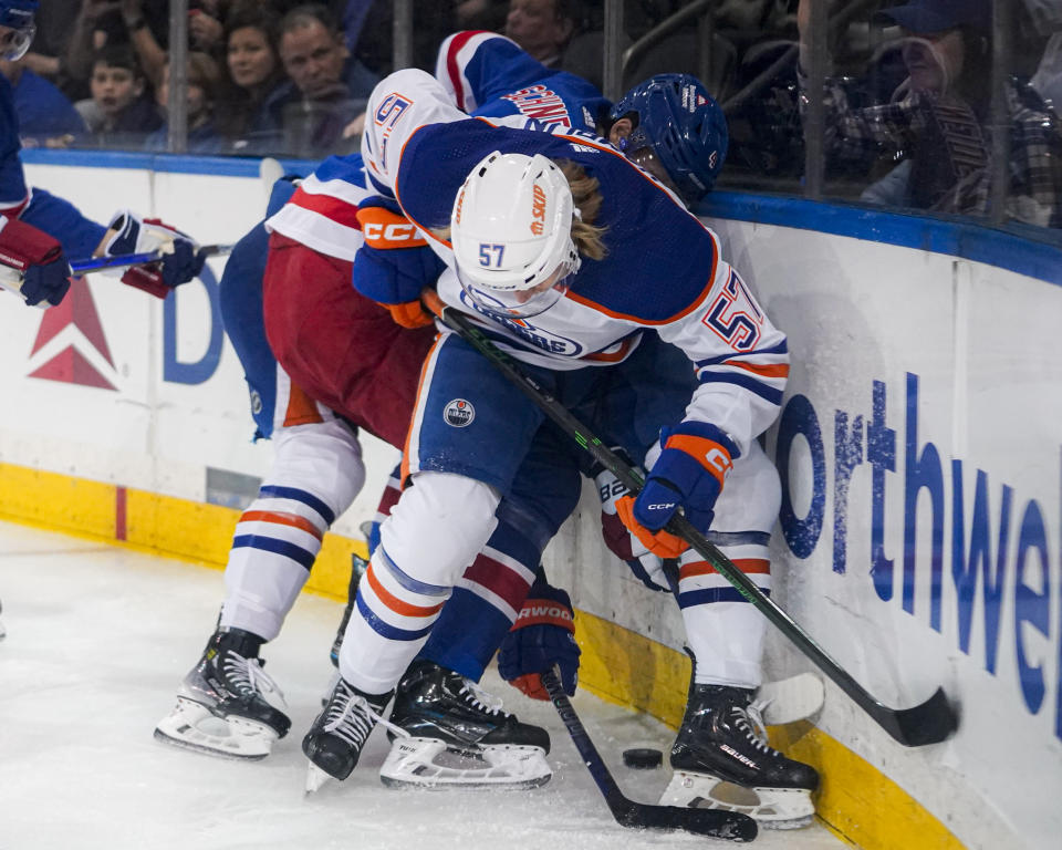 New York Rangers defenseman Braden Schneider (4) and Edmonton Oilers left wing James Hamblin fight for the puck during the first period of an NHL hockey game in New York, Friday, Dec. 22, 2023. (AP Photo/Peter K. Afriyie)