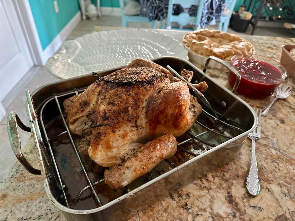 A cooked turkey in a large roasting pan on a counter