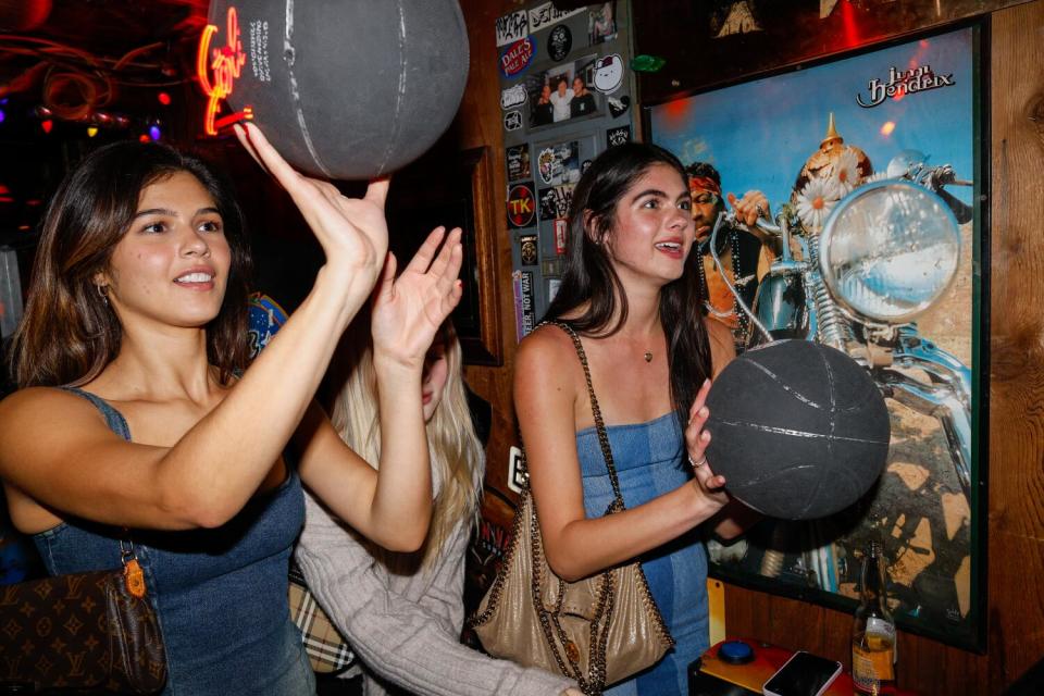 Two young women get ready to throw up black basketballs