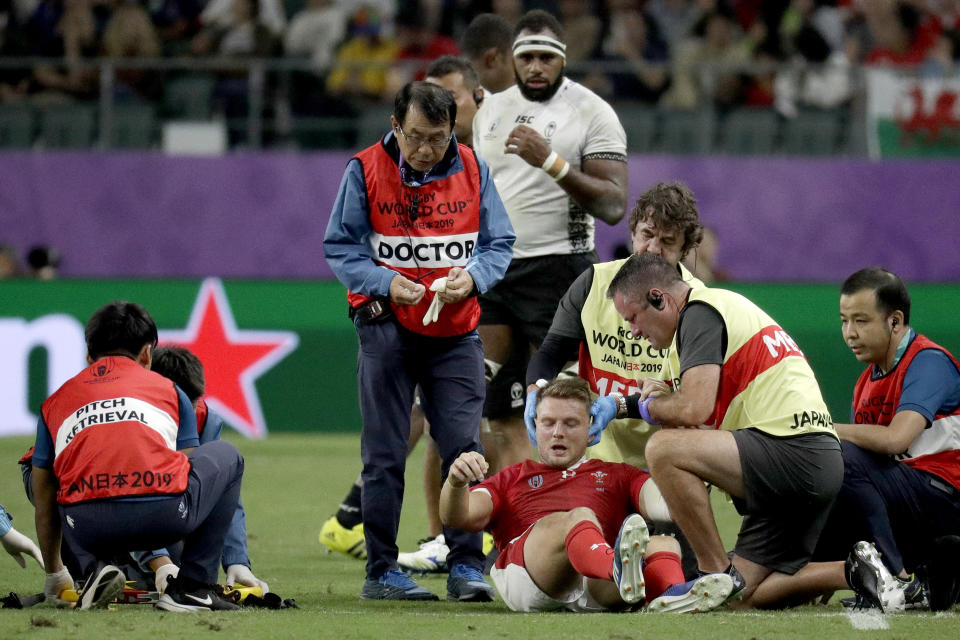 FILE - Wales' Dan Biggar is assisted after he was injured during the Rugby World Cup Pool D game at Oita Stadium between Wales and Fiji in Oita, Japan, on Oct. 9, 2019. The Rugby World Cup will take place to the backdrop of a concussion lawsuit that has similarities to one settled by the NFL in 2013 at a likely cost of more than $1 billion. (AP Photo/Aaron Favila, File)