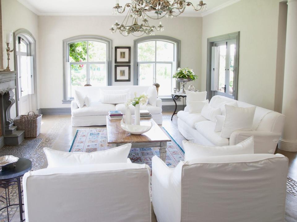 A living room with two white couches and two matching chairs.