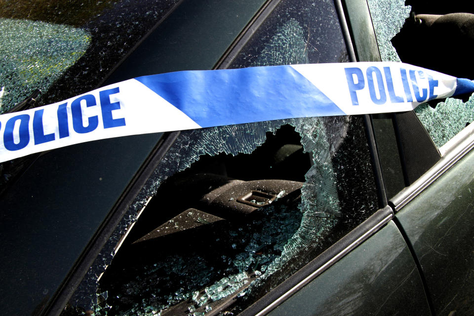 Police tape over a car with broken windows