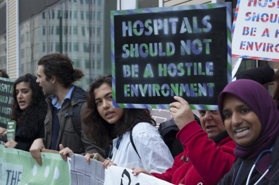 NHS staff and patients, with campaign group Docs Not Cops, are protesting outside the Department of Health against the introduction of immigration checks and upfront charging for NHS patients: Docs Not Cops