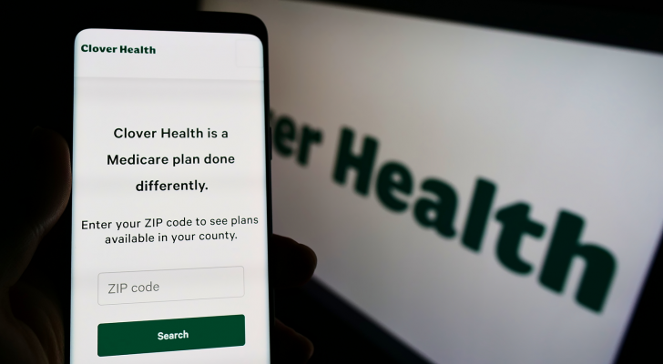 Person holding cellphone with webpage of healthcare company Clover Health Investments Corp on screen with logo Focus on center of phone display. CLOV Stock.