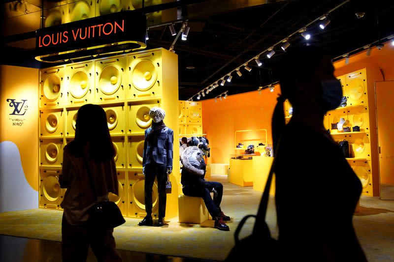 FILE PHOTO: Customers walk past a store of French luxury brand Louis Vuitton inside a shopping mall in Beijing