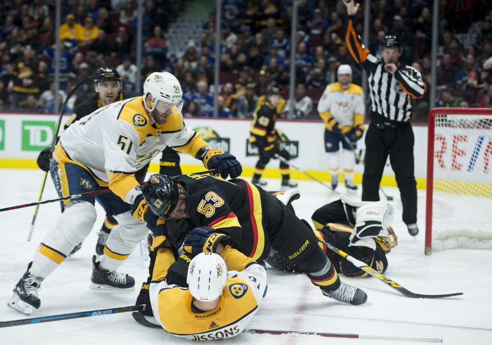 Nashville Predators left wing Austin Watson (51) looks on as Vancouver Canucks center Bo Horvat (53) puts Nashville Predators center Colton Sissons (10) to the ice during the third period of an NHL hockey game, in Vancouver, British Columbia, Monday, Feb. 10, 2020. (Jonathan Hayward/The Canadian Press via AP)