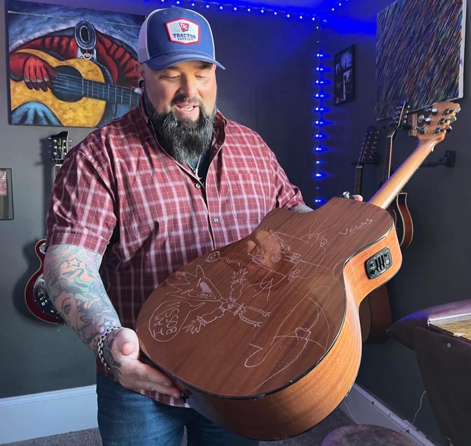 Aaron Hymes displays one of his favorite guitars, which hangs on a wall inside his home in Paris Township. Hymes and his band are recording faith-inspired country music with a music veteran in Nashville.