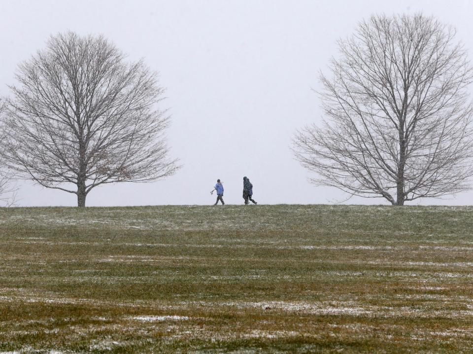 People walk through Brandywine Creek State Park as snow begins to drape the area Saturday morning.