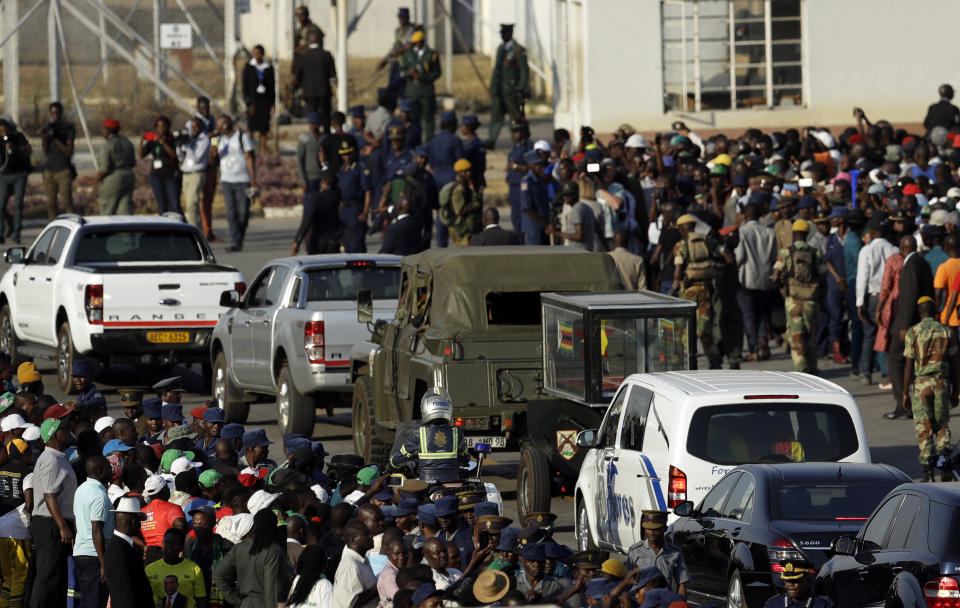 Crowds gather waiting for the hearse carrying the body of the late former President Robert Mugabe drives past during the arrival ceremony at Robert Gabriel Mugabe International Airport in Harare, Zimbabwe, Wednesday, Sept. 11, 2019. (AP Photo/Themba Hadebe)