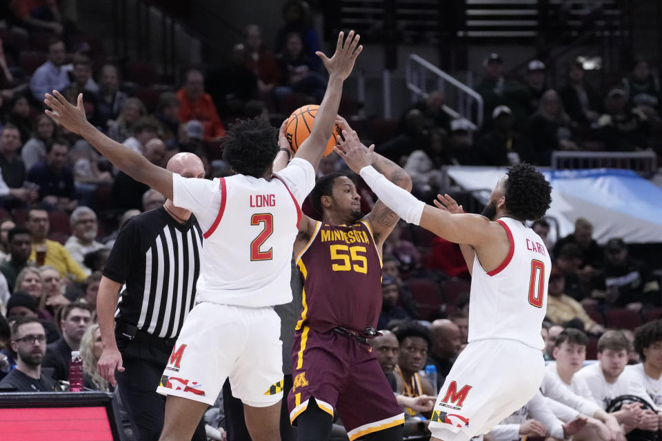 Minnesota's Ta'lon Cooper (55) looks to pass under pressure from Maryland's Jahari Long (2) and Don Carey during the first half of an NCAA college basketball game at the Big Ten men's tournament, Thursday, March 9, 2023, in Chicago. (AP Photo/Charles Rex Arbogast)