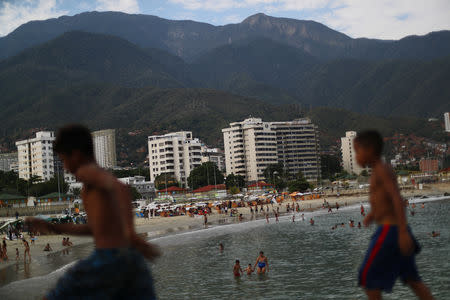 Children walk along a breakwater at Coral beach in La Guaira near Caracas, Venezuela, March 23, 2019. "A person who has a minimum wage can't come [to the beach]. The anguish that has all Venezuelans is food. First the flour and the rice." said Carla Cordova. REUTERS/Ivan Alvarado